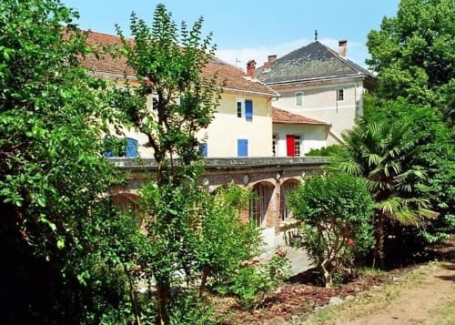 Domaine de Cabrières B&B in St Jean Du Gard with cream-colored walls, blue shutters, ivy-covered courtyard and lush gardens