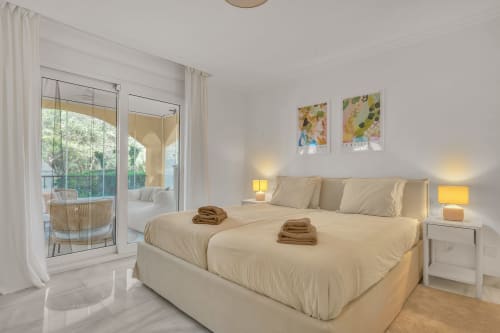 Bright bedroom at Casa Perla Marbella in Elviria with cream bedding, garden views, and modern amenities