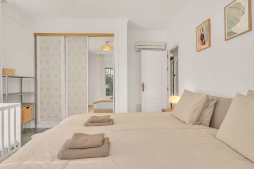 Bright bedroom at HomyMarbella Casa Perla with queen bed, mirrored wardrobe, and garden views in Marbella