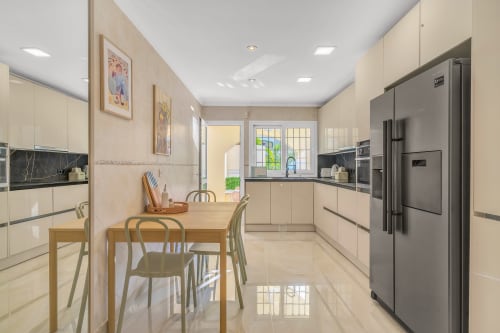 Modern kitchen and dining area in Casa Perla Marbella apartment with cream cabinets, stainless steel appliances, wooden
