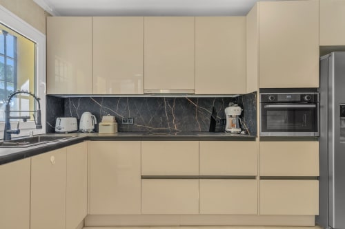 Modern cream kitchen with black marble backsplash at HomyMarbella apartment in Elviria