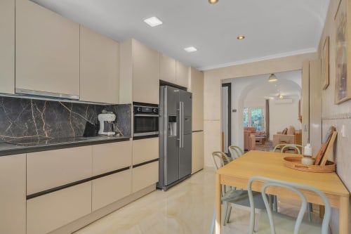 Modern kitchen and dining area at Casa Perla Marbella apartment in Elviria with cream cabinetry, marble backsplash, and