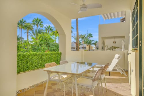 Sunny patio at Casa Perla Marbella with dining table, garden views, and palm trees in Elviria