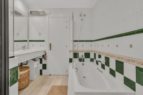 Modern bathroom at HomyMarbella Marbella with white tiles, green accent tiles, bathtub, shower, and sink vanity