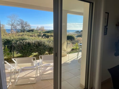 Beachfront apartment terrace at Résidence Marina di Bravone with sea views, white chairs, and coastal garden