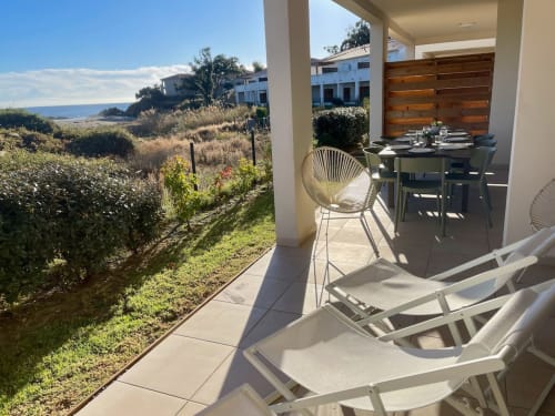 Beachfront terrace at Marina di Bravone with lounge chairs, dining table, and sea views in Linguizzetta