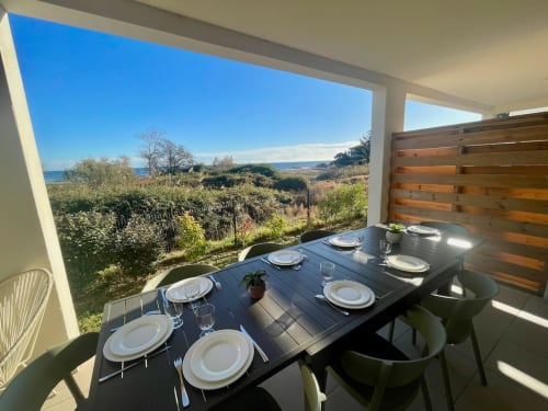 Large apartment balcony at Résidence Marina di Bravone with dining table, sea views, and Corsican landscape