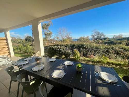 Outdoor dining table set on covered terrace at Marina di Bravone, Linguizzetta, with beach views and gardens
