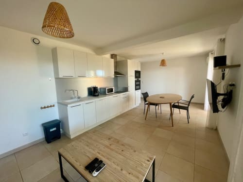 Modern open-plan kitchen and living area at Résidence Marina di Bravone apartment, Linguizzetta, with white cabinetry and