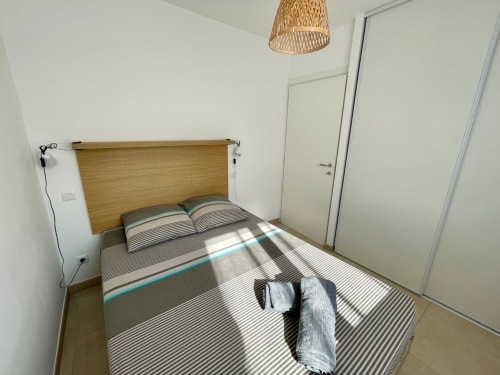 Bright bedroom at Résidence Marina di Bravone with wooden headboard, striped bedding, and modern minimalist decor