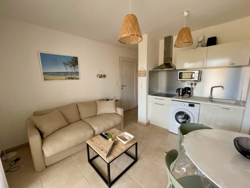 T2 apartment at Résidence Marina di Bravone in Linguizzetta featuring beige sofa, kitchen with appliances, and modern