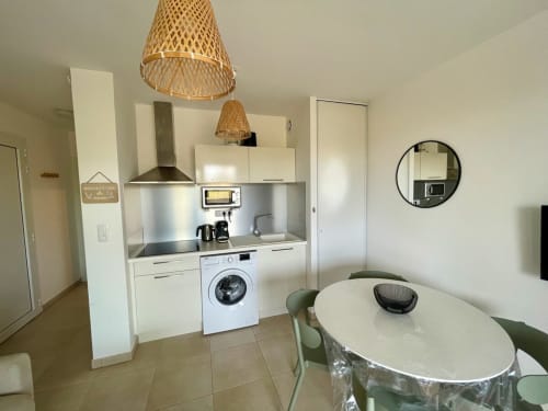 Modern kitchenette with dining area at Résidence Marina di Bravone, Linguizzetta. White cabinetry, washing machine, woven