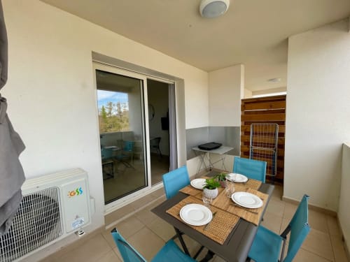Modern dining area in Marina di Bravone apartment with table, blue chairs, and sea view balcony