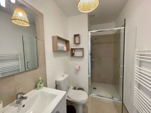 Bagno moderno presso Résidence Marina di Bravone con lavabo, toilet, doccia, specchio e scaffali in legno