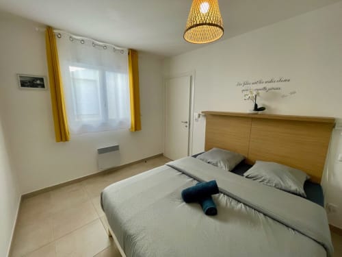 Camera moderna della Résidence Marina di Bravone a Linguizzetta con letto matrimoniale, testata in legno e lampadario dorato