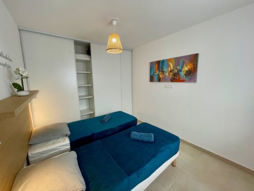 Camera da letto moderna presso Résidence Marina di Bravone con divano letto blu, mobili in legno e quadri colorati alle pareti.