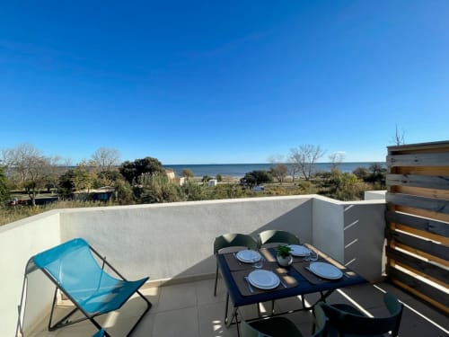 Terrazza panoramica a Marina di Bravone con tavolo da pranzo, sedia blu, vista sul mare e paesaggio costiero a Linguizzetta