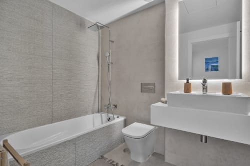 Nowoczesna łazienka w townhouse HomyMarbella z białą umywalką, toaletą, wanną i prysznicem za szklaną przegrodą, szare kafelki na ścianach