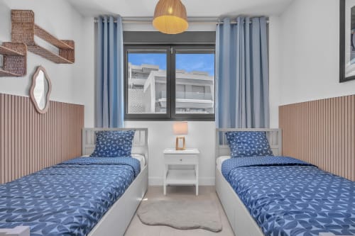 Sypialnia z łóżkami bliźniaczymi w Townhouse Eden Golf Chaparral w HomyMarbella, Elviria z niebieską pościelą we wzory, drewnianymi ścianami akcentujący
