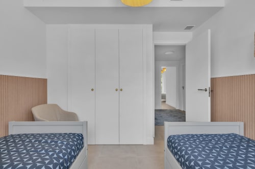 Nowoczesna sypialnia z łóżkami bliźniaczymi w HomyMarbella Townhouse Eden Golf Chaparral w Elvirii, wyposażona w białe szafy i drewniany wystrój ścian