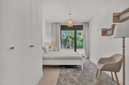 Nowoczesna sypialnia w townhouse HomyMarbella z widokiem na ogród, białym łóżkiem, półkami z rattanu i dostępem na balkon w Elvirii