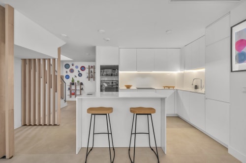 Nowoczesna biała kuchnia z wyspa i drewnianymi stołkami w townhouse HomyMarbella, Elviria Hiszpania