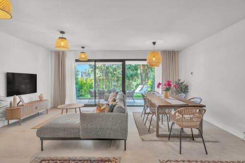 Nowoczesny salon w rezydencji HomyMarbella z widokiem na ogród, szarą sofą, strefą jadalną i dostępem do tarasu