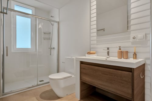Nowoczesna łazienka w apartamencie HomyMarbella z białymi kaflami metrażowymi, drewnianą umywalką, prysznicem i widokami na góry w Elvirii