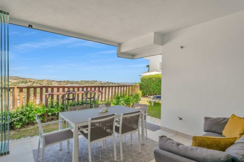 Nowoczesny balkon apartamentu HomyMarbella Elviria ze stołem jadalnianym, widokami na góry i urządzoną rezerwą zieloną