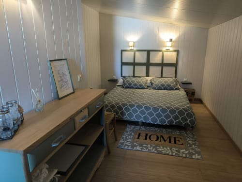 Chambre moderne du gîte de la vallée avec lit queen-size, bureau, linge de lit à motifs et éclairage naturel sur le jardin
