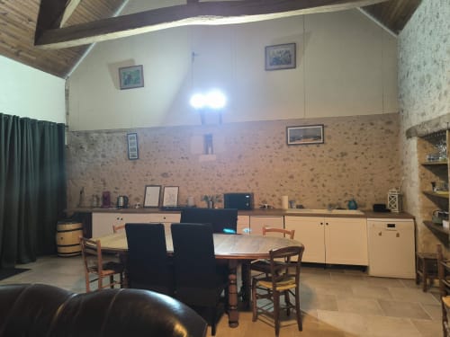 Spacieux séjour du gîte avec murs en liège, poutres bois, cuisine équipée et table à manger