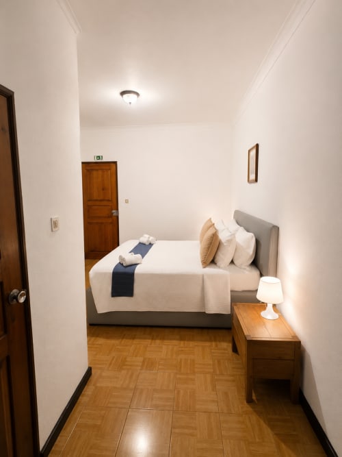 Quarto moderno na Pousada Serrana Gerês com cama queen, criado de madeira e piso de parquete em Gerês, Portugal