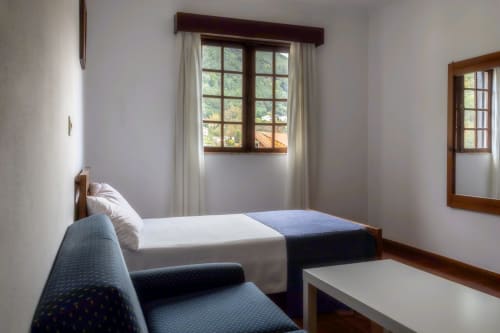 Quarto duplo padrão na Pousada Serrana Gerês com cama, janelas com vista para a natureza e móveis modernos em Gerês, Portugal