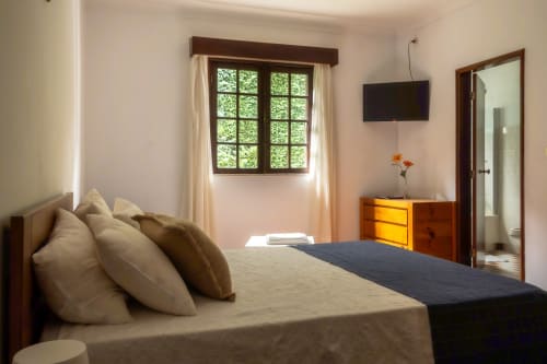 Quarto duplo standard na Serrana Gerês Inn com cama, móveis de madeira, janela com vista para o jardim e TV em Gerês, Portugal