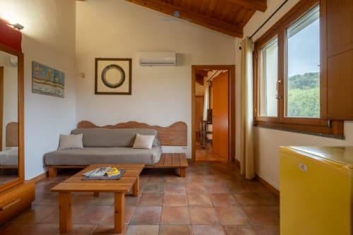 Soggiorno della Suite Locandiere presso House Live Express a Quartu Sant'Elena con futon in legno, pavimenti in cotto e giardino