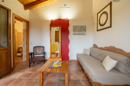 Suite Locandiere presso House Live Express a Quartu Sant'Elena con divano, travi in legno, parete rossa e vista sul giardino