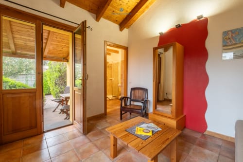 Zona living Locandiere Suite con travi in legno, pavimenti in cotto, parete rossa e vista sul giardino presso House Live Express