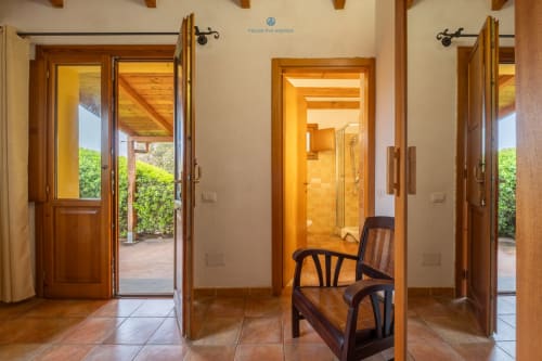 Corridoio della Suite Locandiere con porte in legno, pavimenti in cotto e vista sul giardino presso House Live Express a Quartu Sant'elena