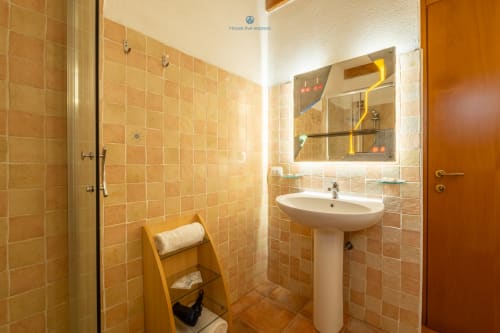 Bagno moderno con piastrelle arancioni, lavabo a piedistallo, specchio illuminato e doccia nella Suite Locandiere di House Live Express