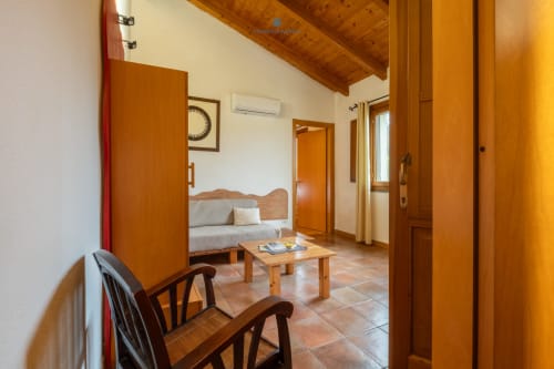 Suite Locandiere presso House Live Express a Quartu Sant'Elena con travi in legno, pavimenti in cotto, divano e vista sul giardino