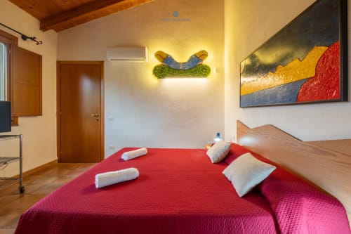 Camera Locandiere Suite moderna presso House Live Express con letto rosso, travi in legno, pareti gialle e arte contemporanea