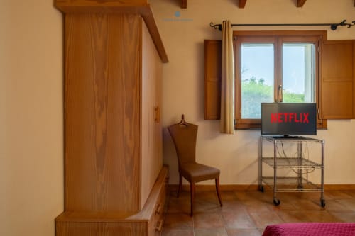 Camera Locandiere Suite con armadio in legno, TV su mobile, poltrona e vista sul giardino presso House Live Express a Quartu Sant'Elena