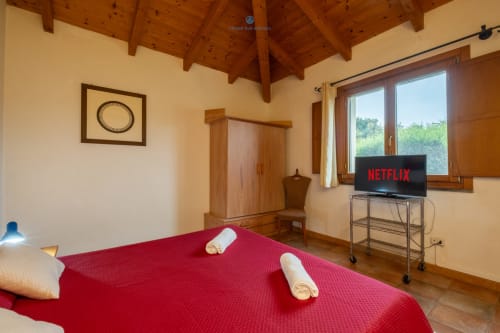 Camera Locandiere Suite presso House Live Express con letto rosso, travi in legno, TV con Netflix e vista sul giardino