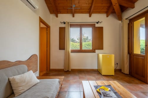 Camera Locandiere Suite presso House Live Express con travi in legno, pavimenti in cotto, finestre con vista sul giardino e minibar giallo