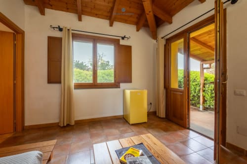 Luminosa Suite Locandiere con travi in legno, pavimento in cotto, frigorifero giallo e porte in legno che si affacciano sul giardino