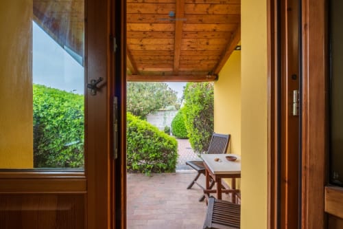 Vista giardino della Suite Locandiere presso House Live Express a Quartu Sant'Elena con arredi in legno e siepi verdi rigogliose