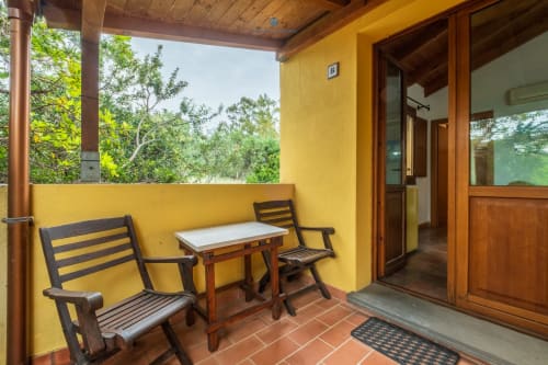 Balcone giallo con due sedie nere e tavolo bianco affacciato sul giardino di House Live Express, Quartu Sant'elena