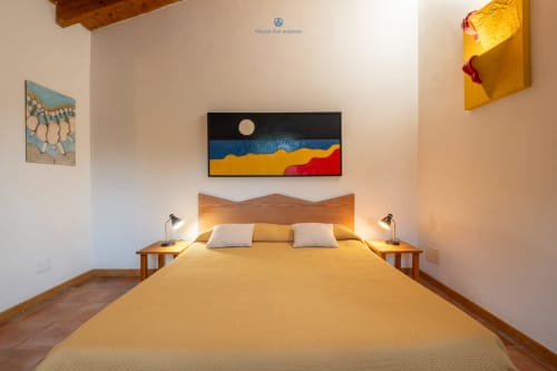 Suite Locandiere della House Live Express con letto in legno, biancheria gialla, cuscini bianchi e astratto colorato