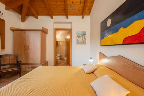 Camera Locandiere della House Live Express a Quartu Sant'Elena con soffitto in legno, biancheria gialla e arte moderna