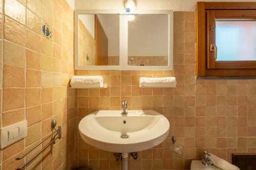 Bagno moderno dell'hotel House Live Express con lavabo bianco rotondo, armadietti a specchio, pareti in cotto e porta asciugamani